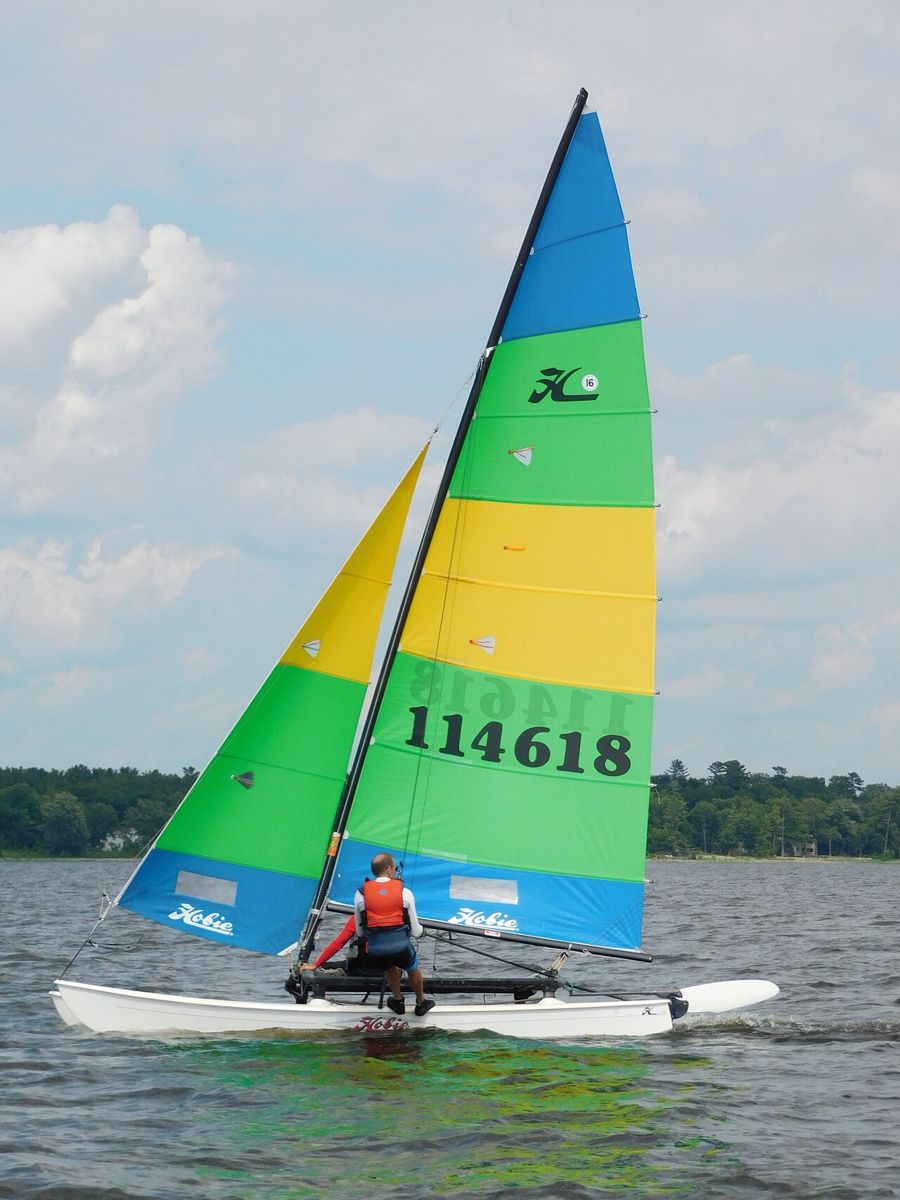 A Hobie 16 with a yellow and white mainsail sailing on a lake